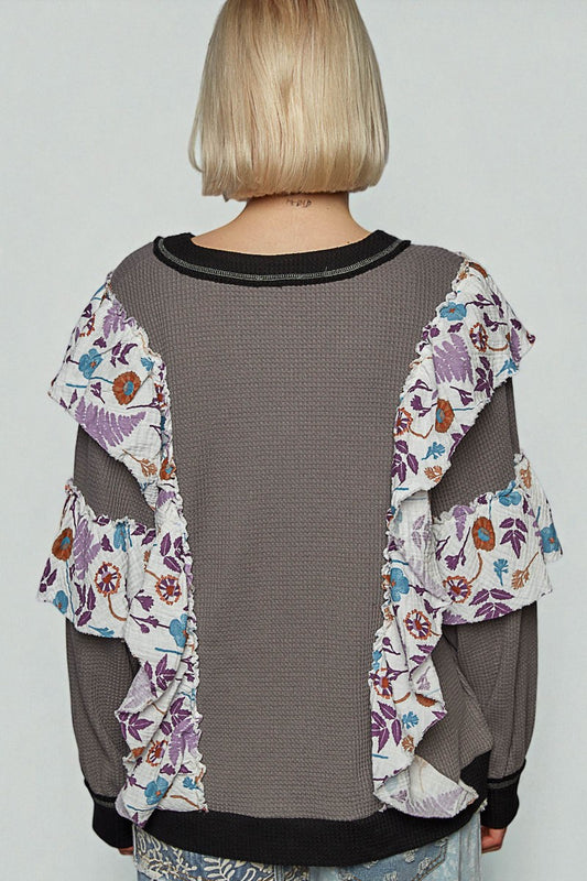 Person wearing a gray mesh top with floral sleeves against a white background