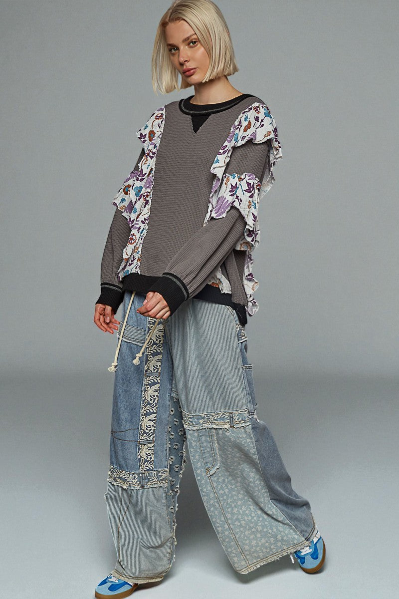 Person wearing a floral jacket, gray top, and wide-leg jeans on a gray background