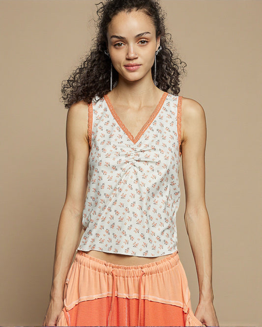 Woman wearing a floral top and orange skirt against a beige background