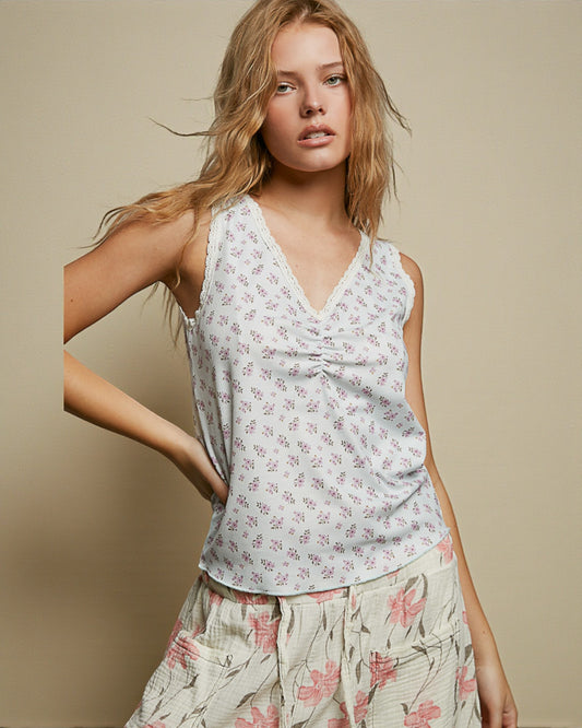 Woman wearing a floral sleeveless top and pants against a beige background