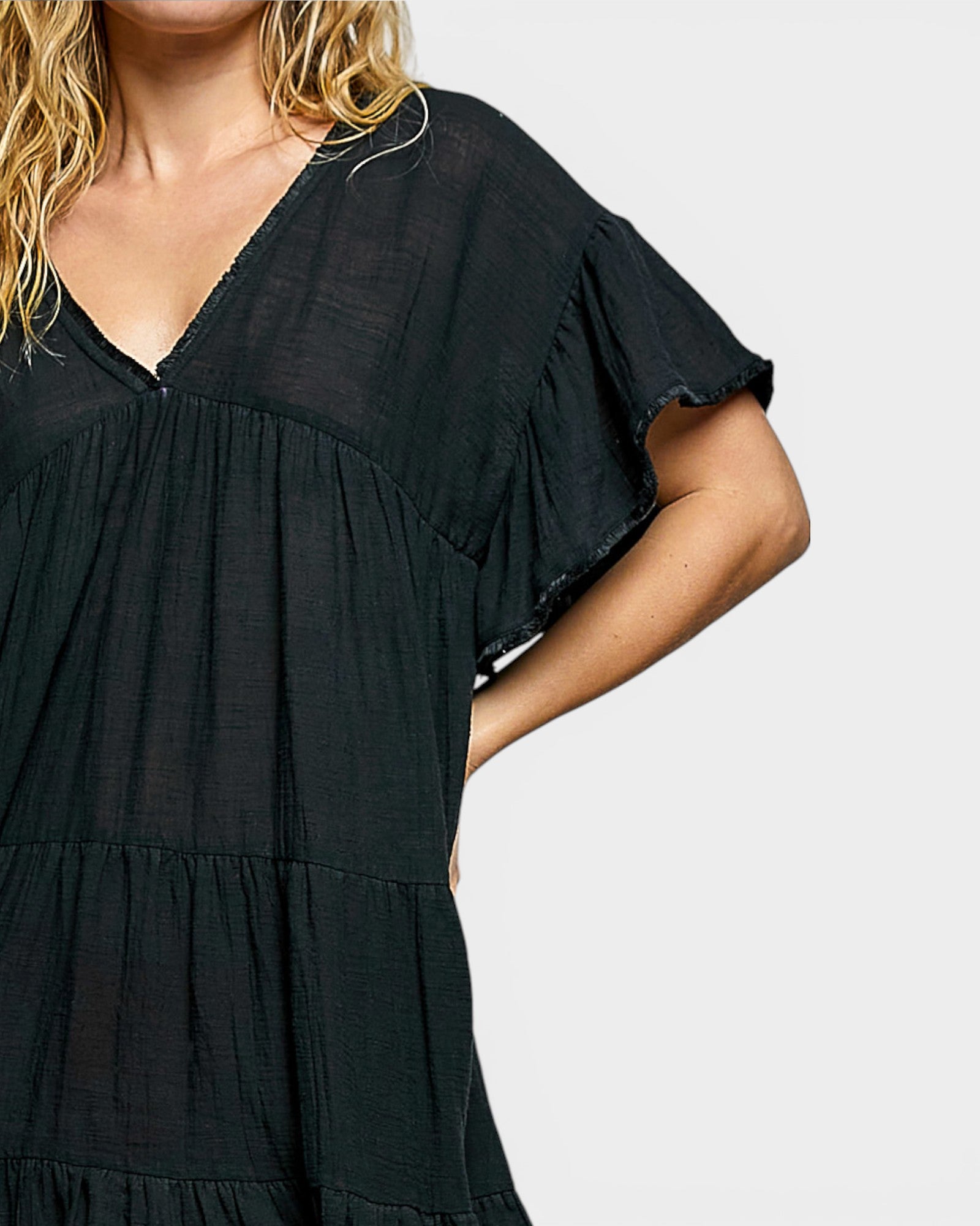 Black tiered dress worn by a person on a plain background