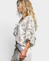Woman wearing a floral blouse with ruffled sleeves on a plain background