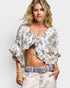 Woman wearing a floral blouse with ruffled sleeves on a plain background