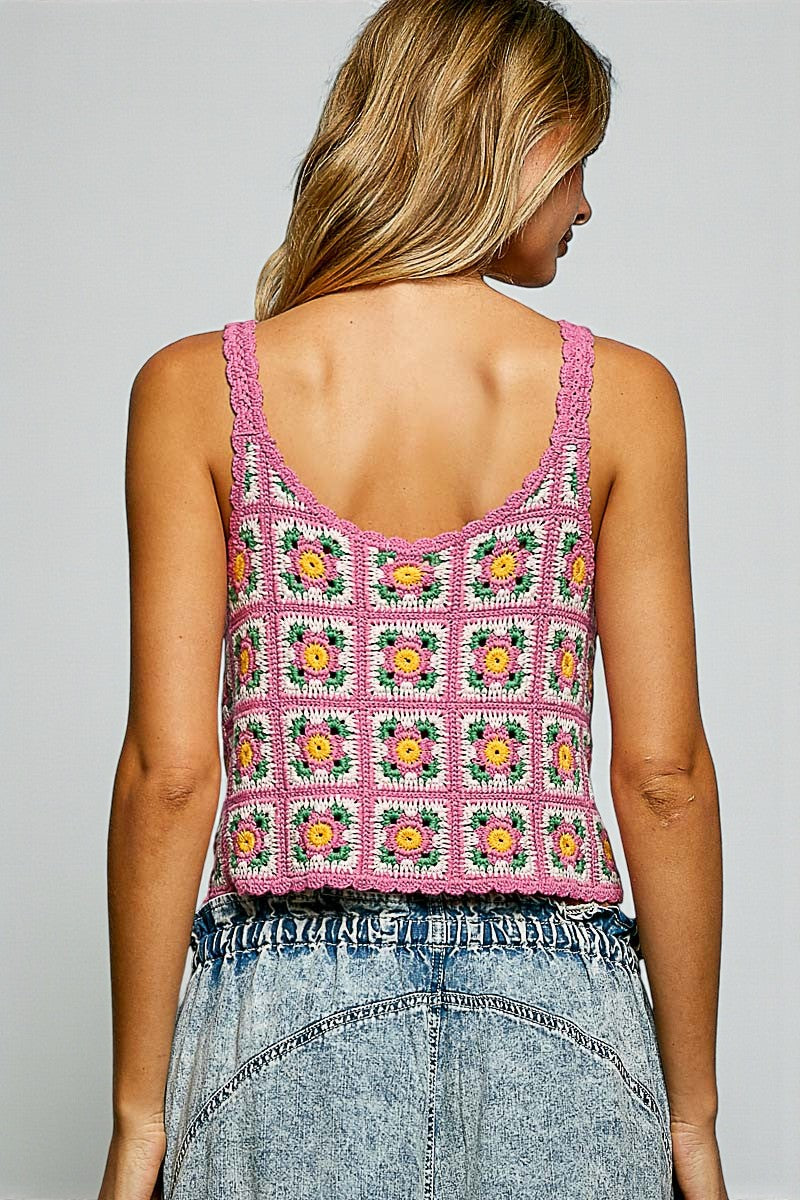 Person wearing a colorful crochet tank top with a plain background