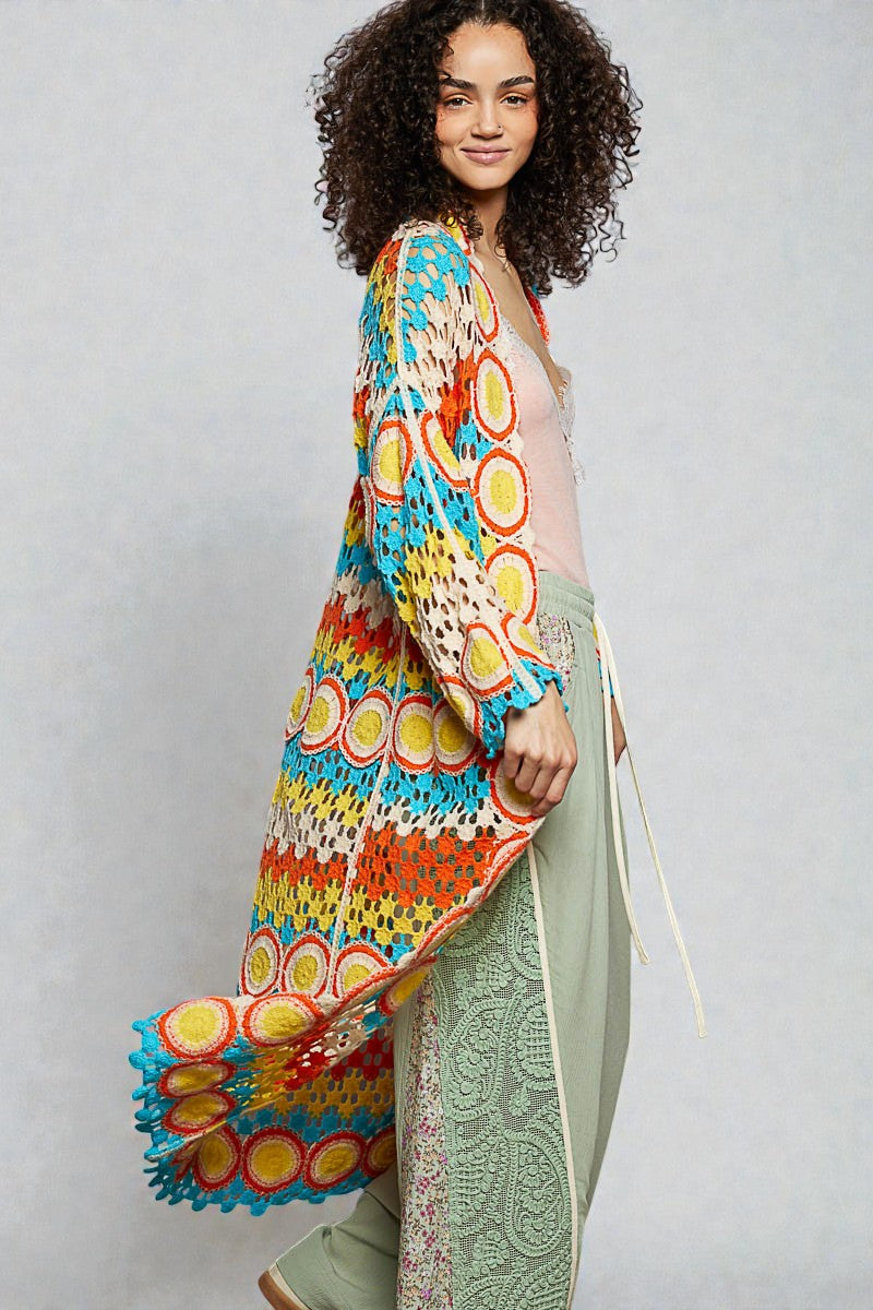 Woman wearing a colorful patterned kimono over a light green dress on a plain background