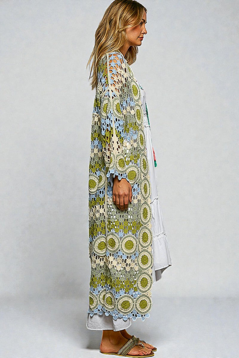 Woman wearing a long, patterned kimono-style garment against a plain background