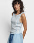 Woman wearing a light blue sleeveless top with a subtle pattern on a plain background