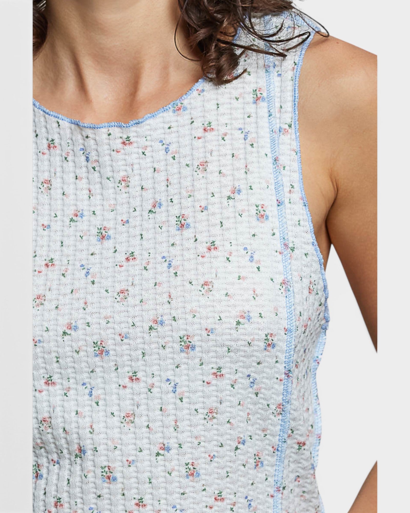 Close-up of a sleeveless top with a floral pattern on a plain background