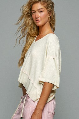 Woman wearing a white top and pink pants against a gray background