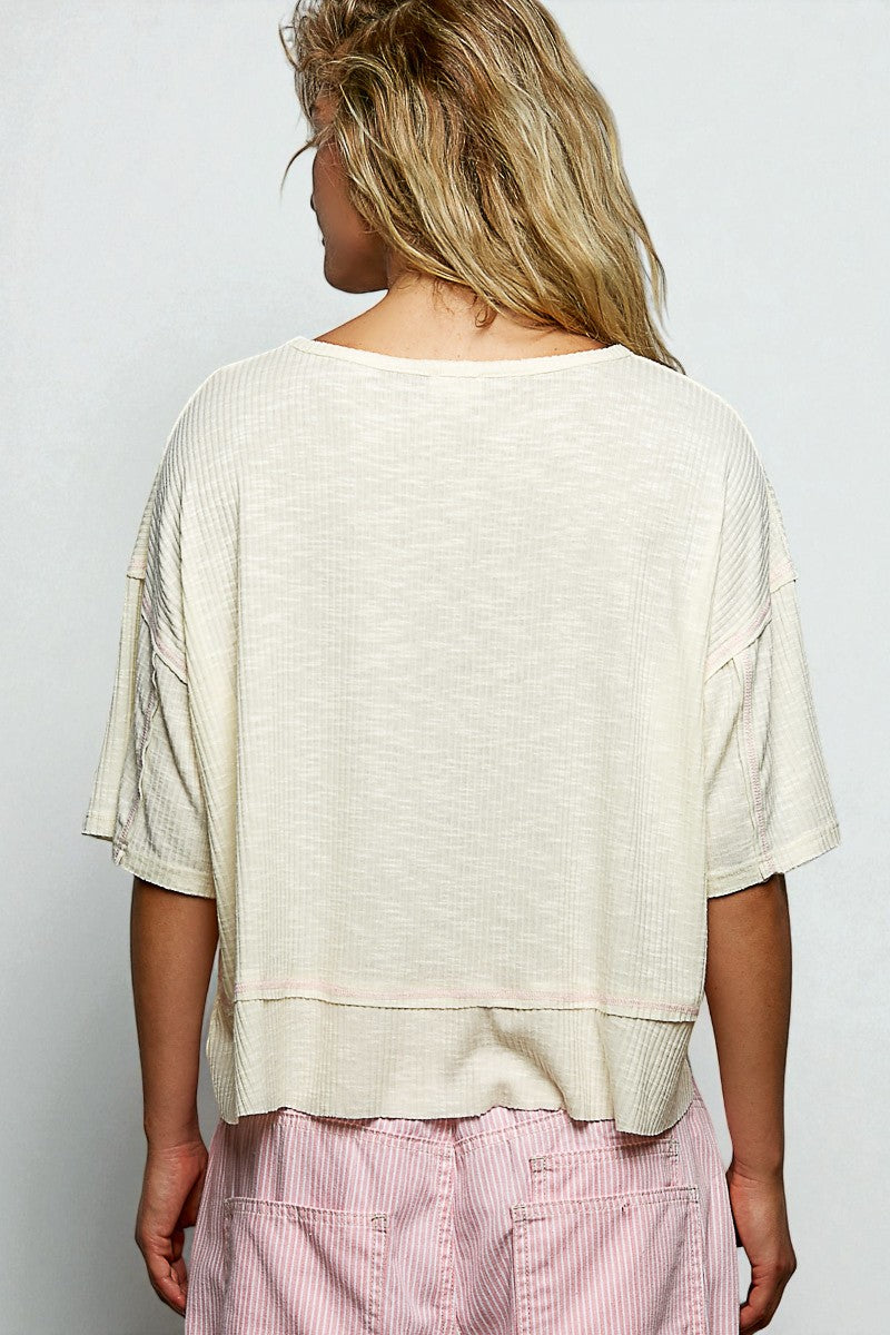 Person wearing a beige top and pink pants against a white background