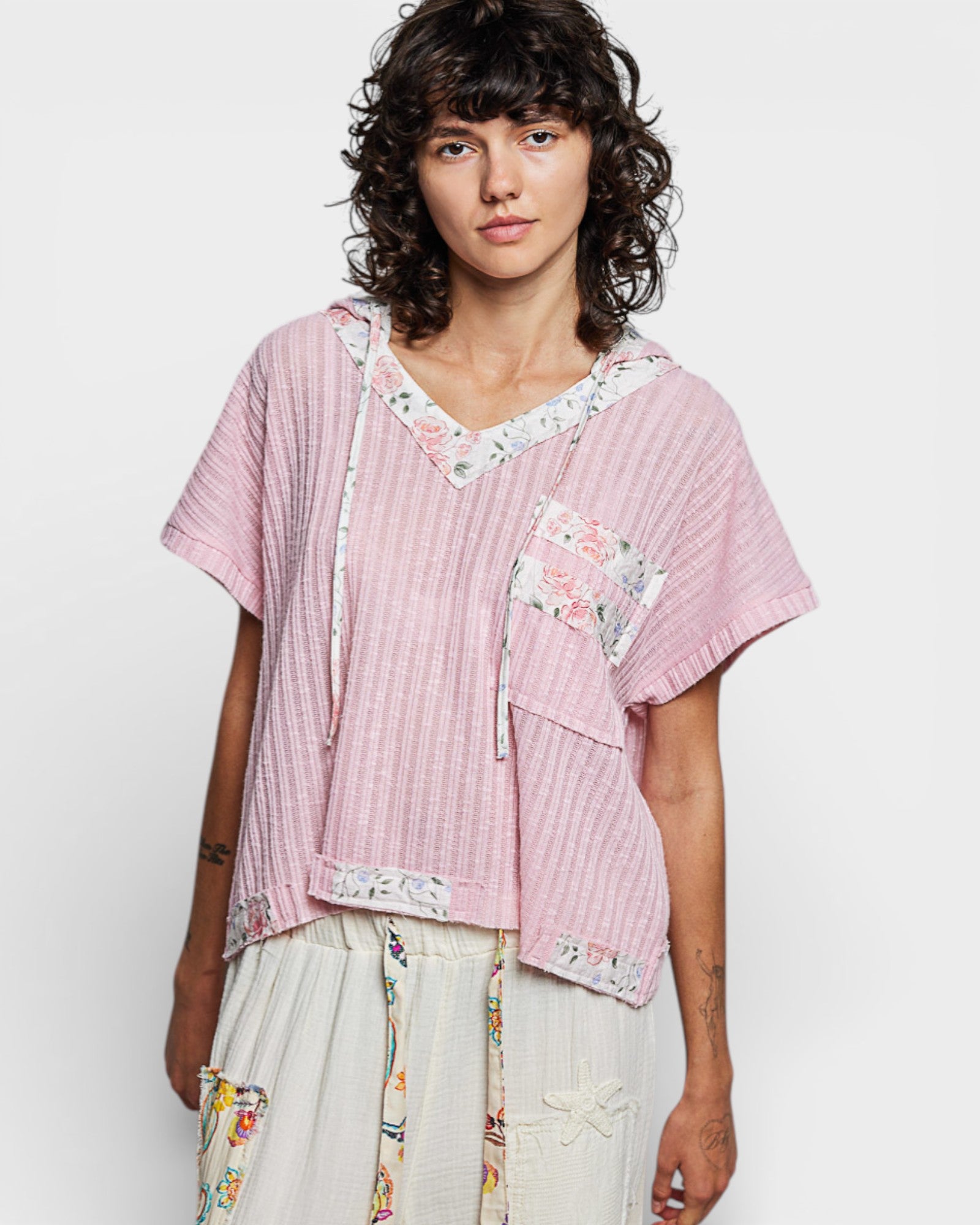 Woman wearing a pink blouse with floral patterns on a white background
