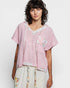 Woman wearing a pink blouse with floral patterns on a white background