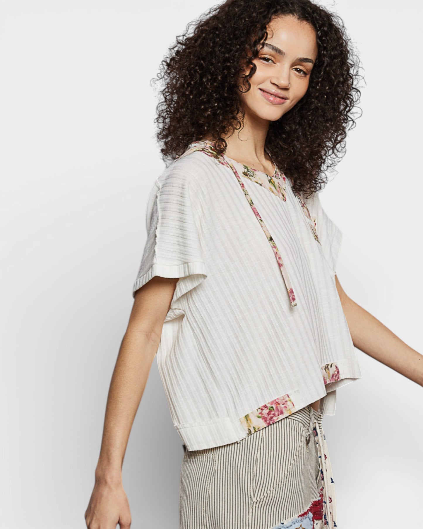 Woman wearing a light-colored blouse with floral details on a white background
