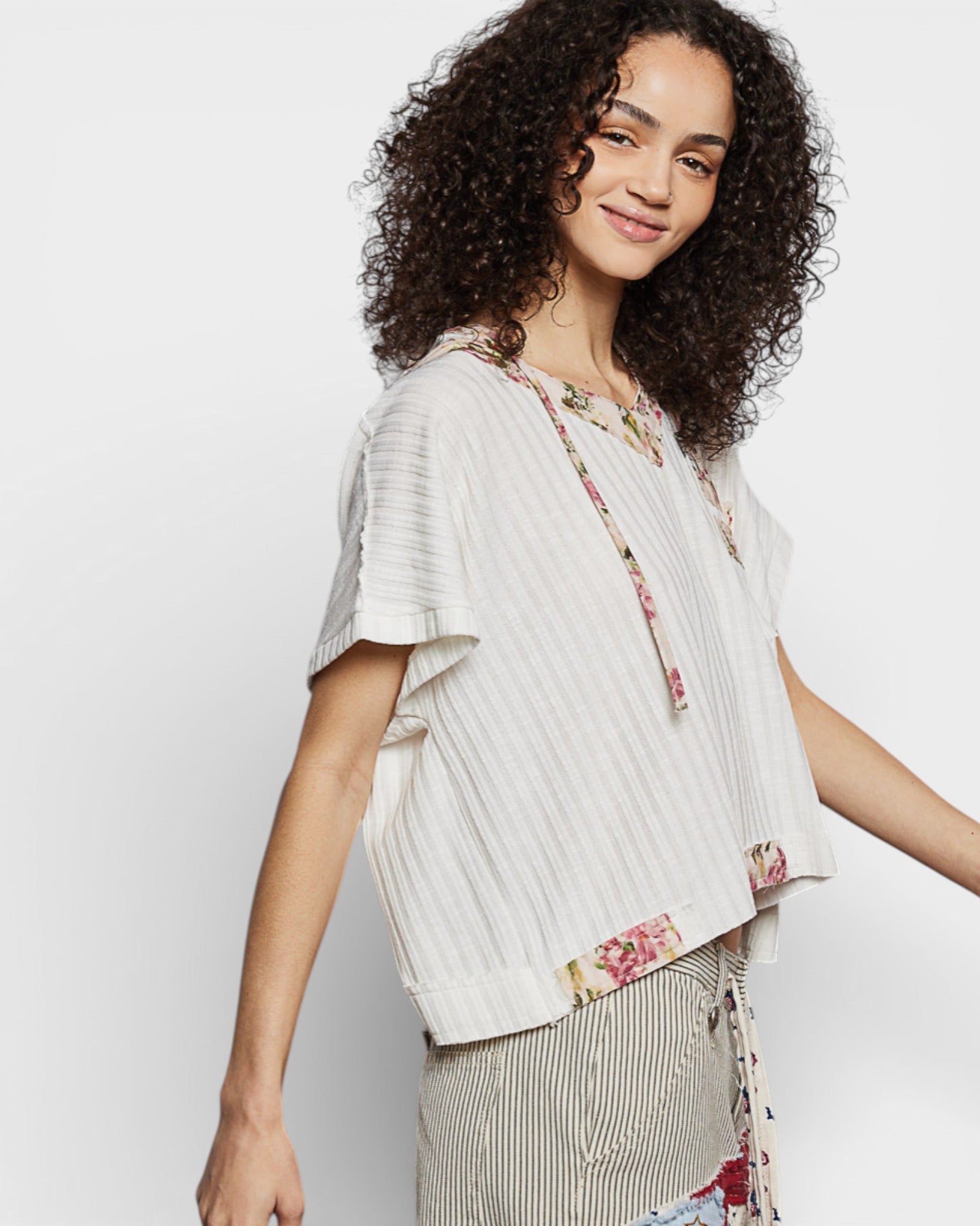 Woman wearing a light-colored blouse with floral details on a white background