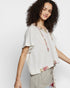 Woman wearing a light-colored blouse with floral details on a white background