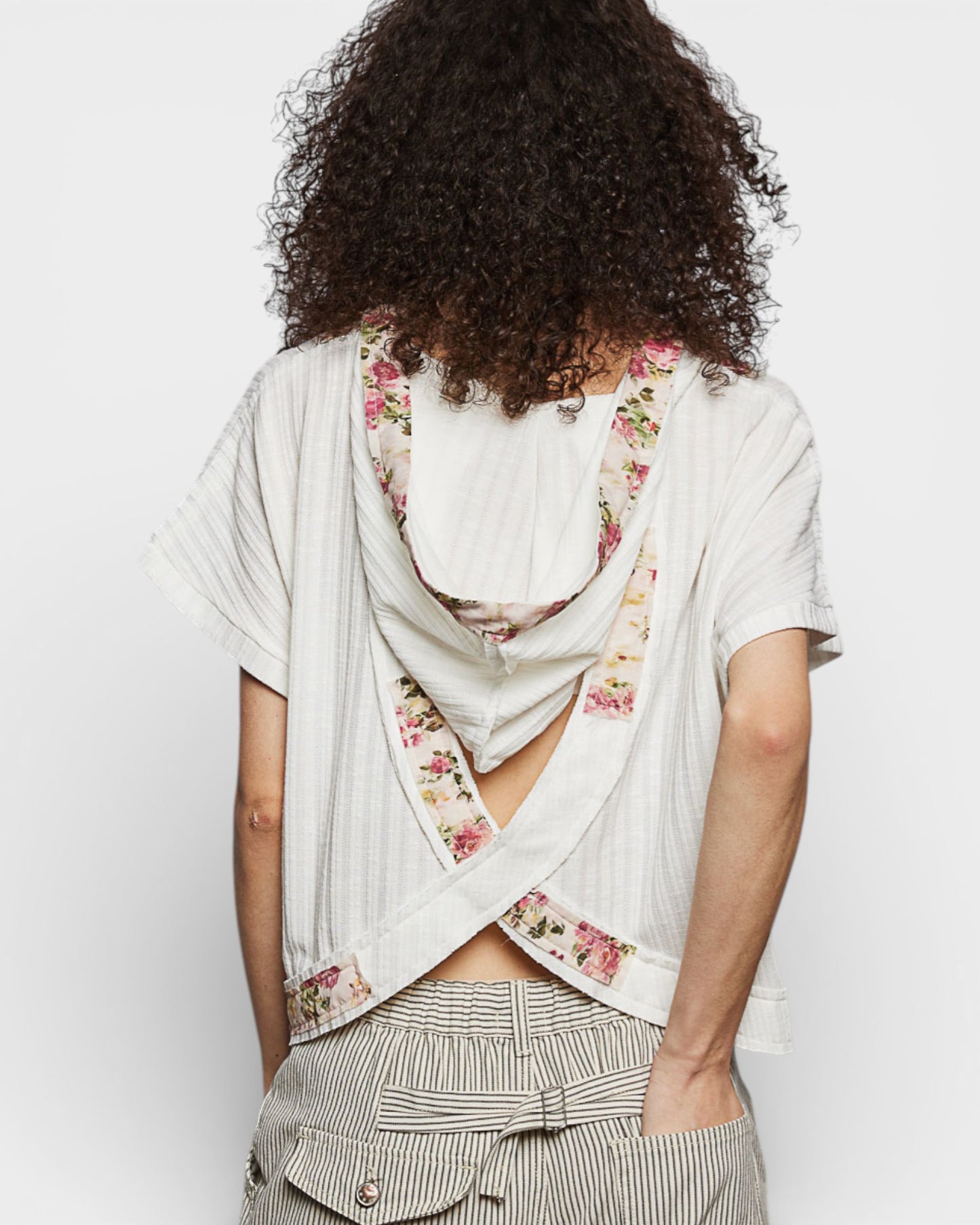 Person wearing a floral scarf over a white shirt with a plain background