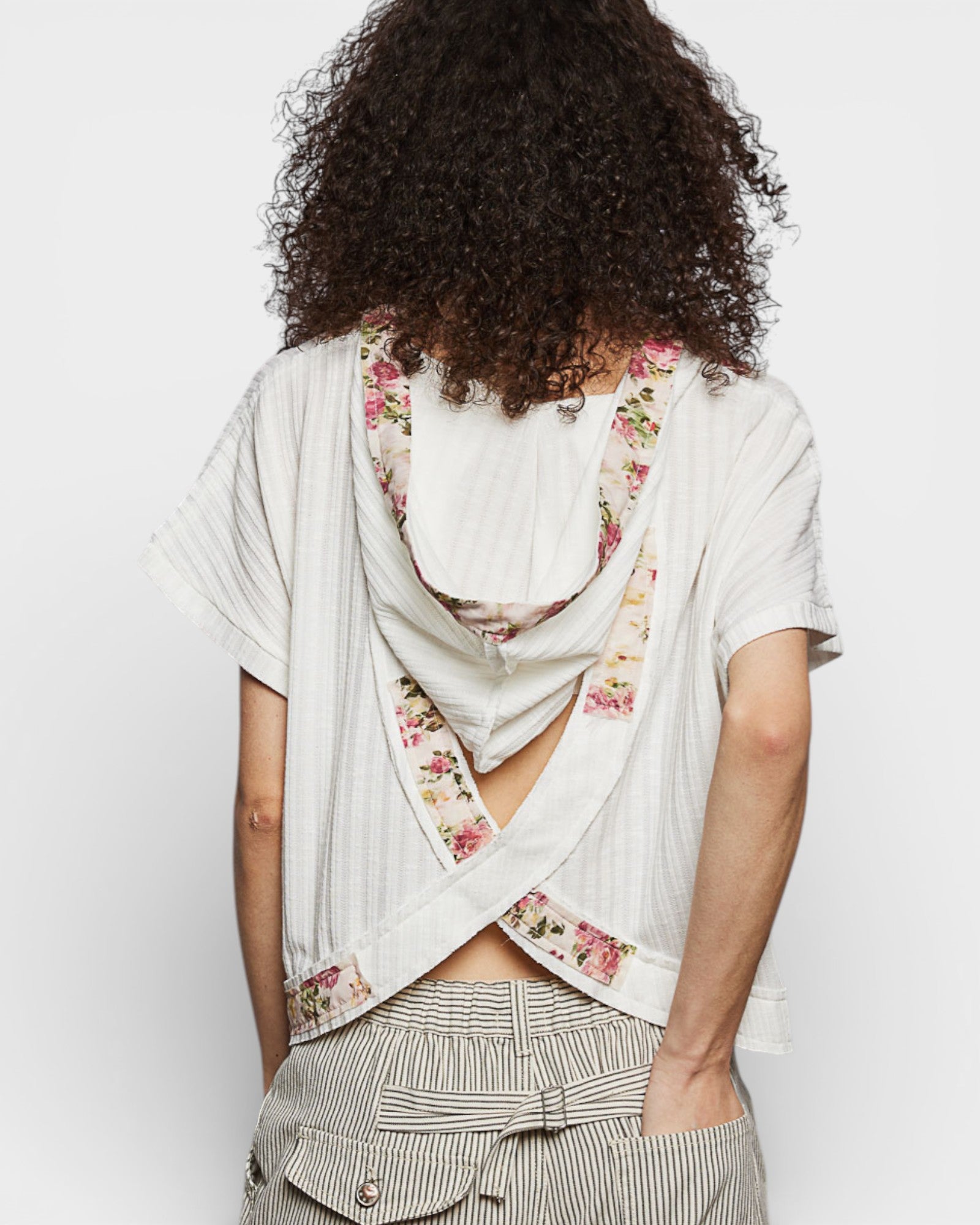 Person wearing a floral scarf over a white shirt with a plain background