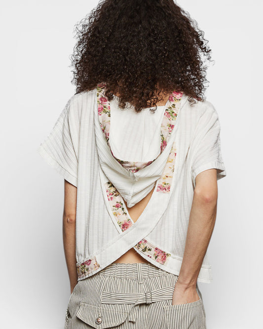 Person wearing a floral scarf over a white shirt with a plain background