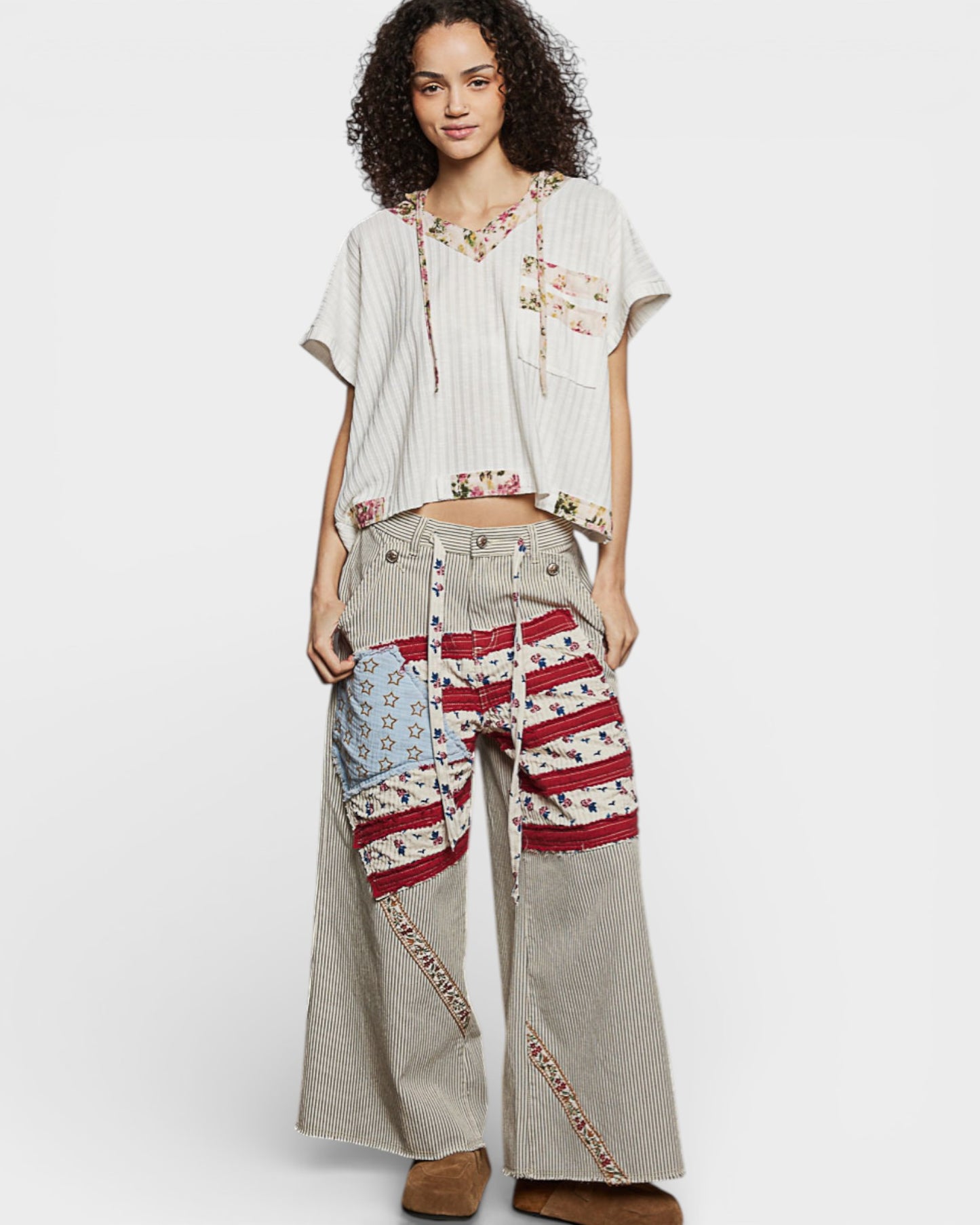 Woman wearing a casual outfit with a patterned top and wide-leg pants on a white background