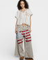 Woman wearing a casual outfit with a patterned top and wide-leg pants on a white background