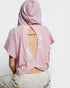 Person wearing a pink textured top with floral patches on a white background