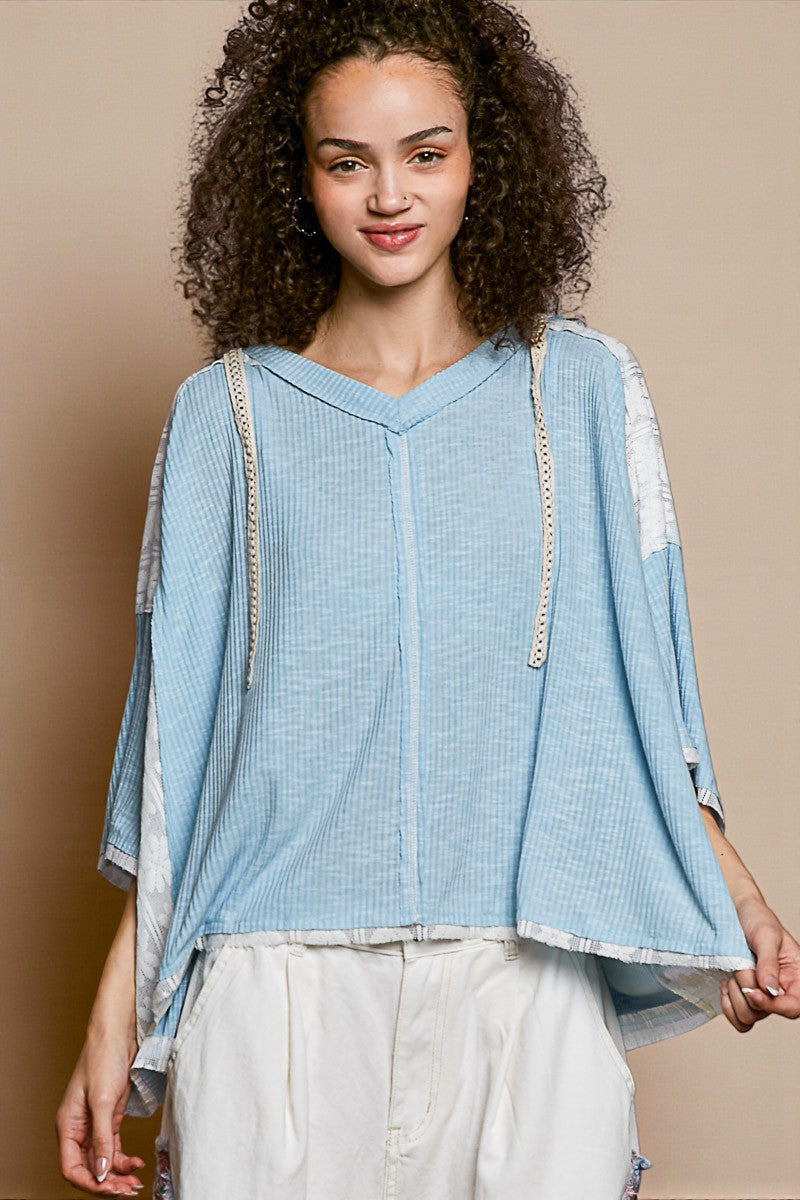 Woman wearing a light blue top with lace details on a beige background