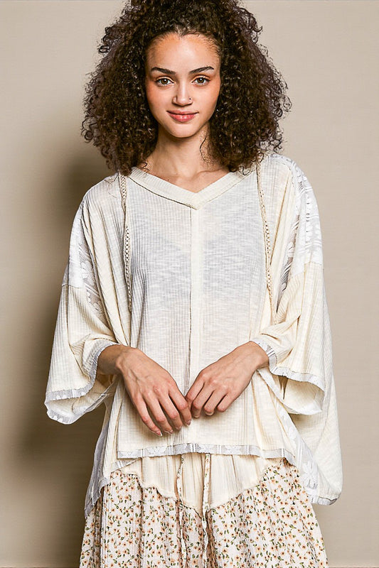 Woman wearing a white blouse with sheer sleeves against a beige background