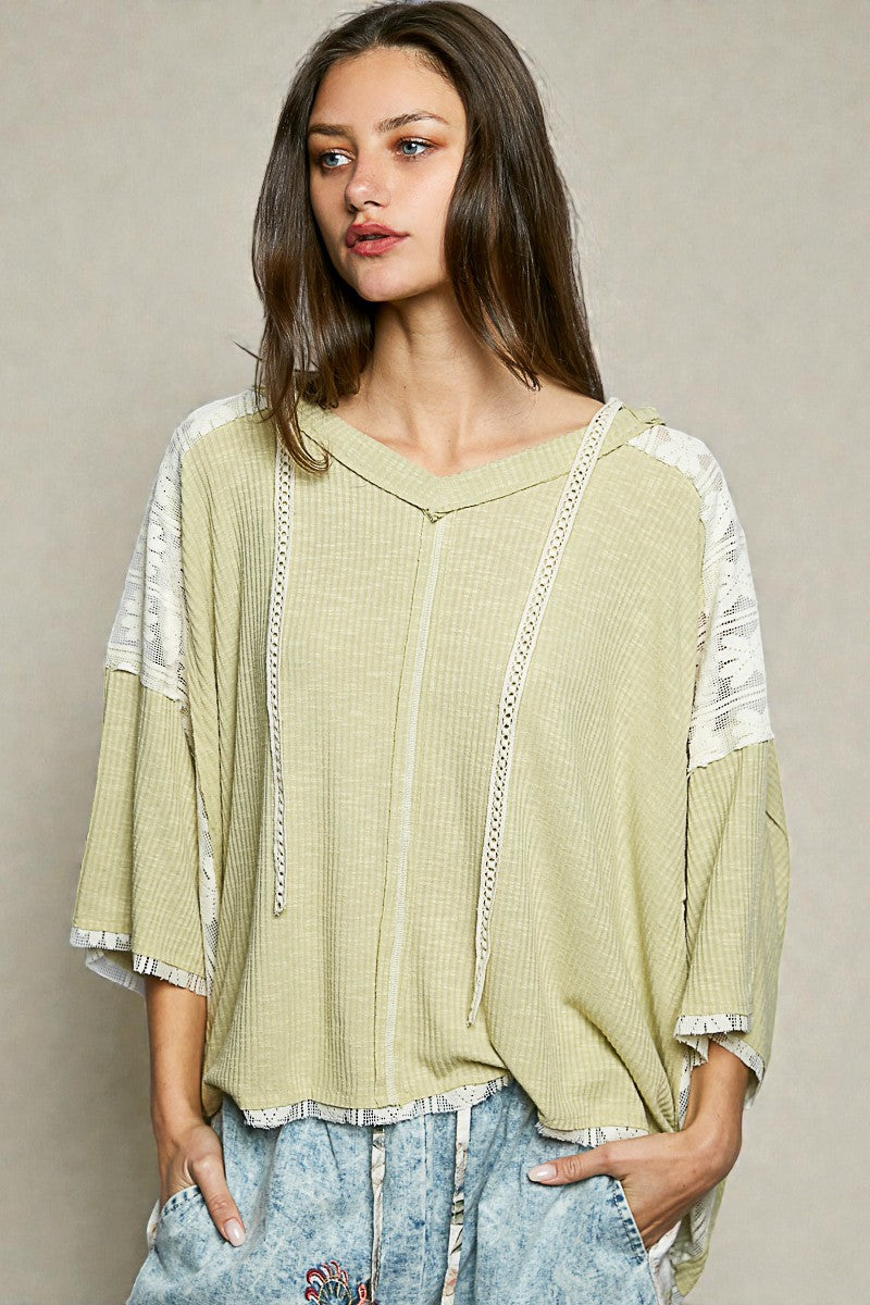 Woman wearing a light green blouse with lace details on a beige background