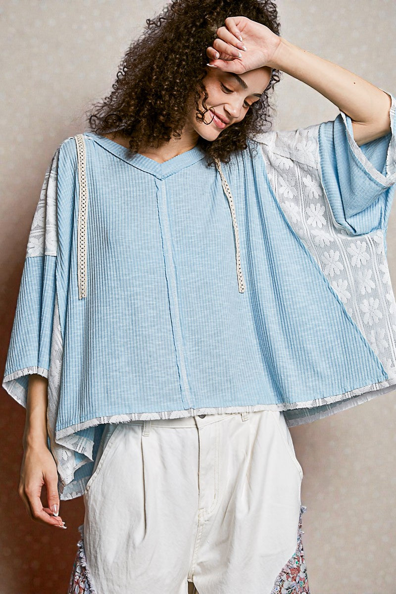 Woman wearing a light blue and white patterned top with a neutral background