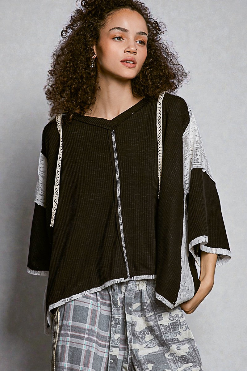 Woman wearing a black top with white trim and plaid pants against a gray background