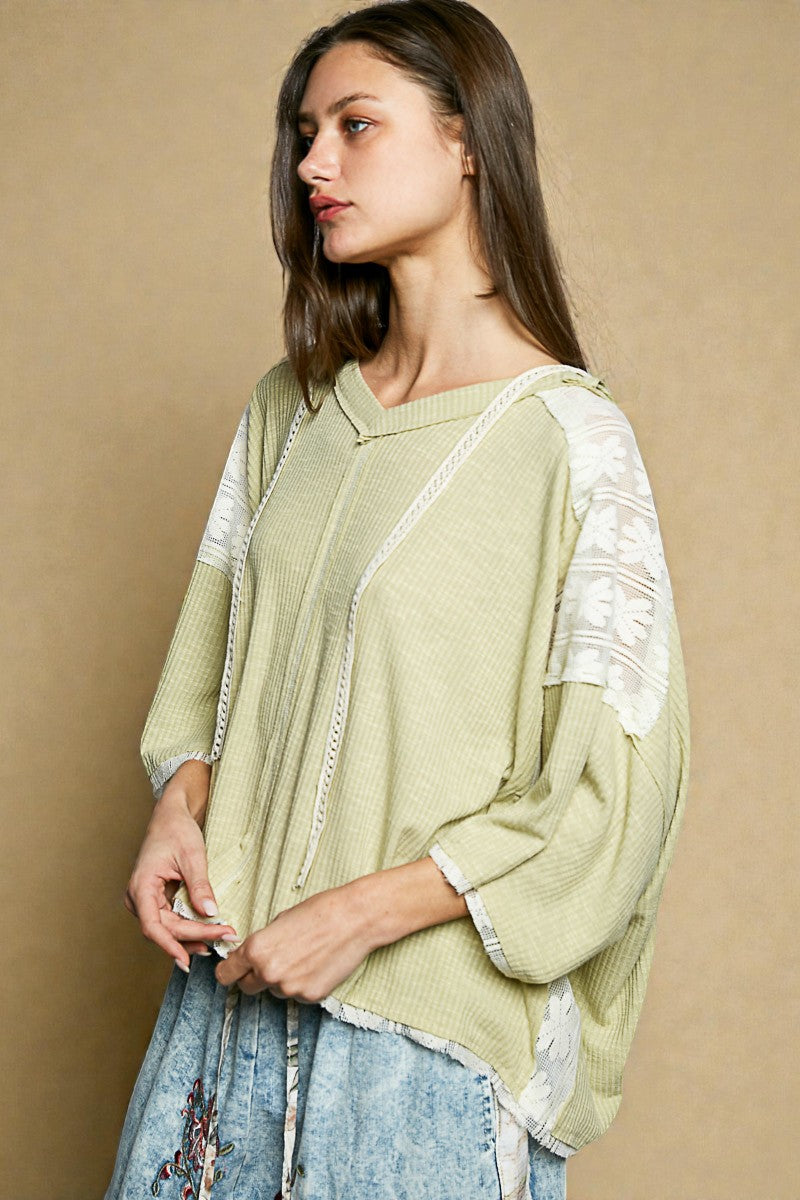 Woman wearing a light green sweater with lace details on a beige background