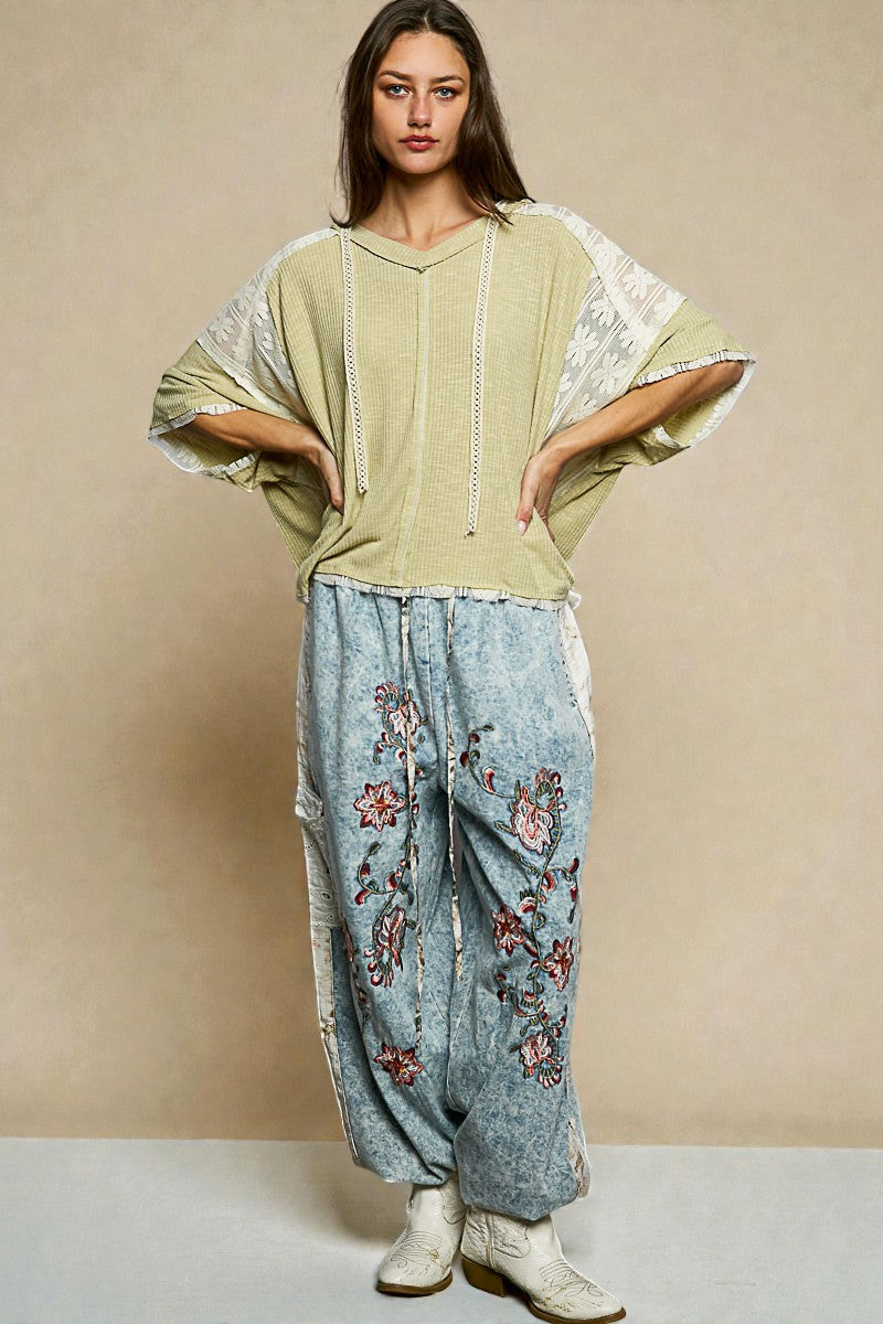 Woman wearing a light green top and blue floral pants against a beige background