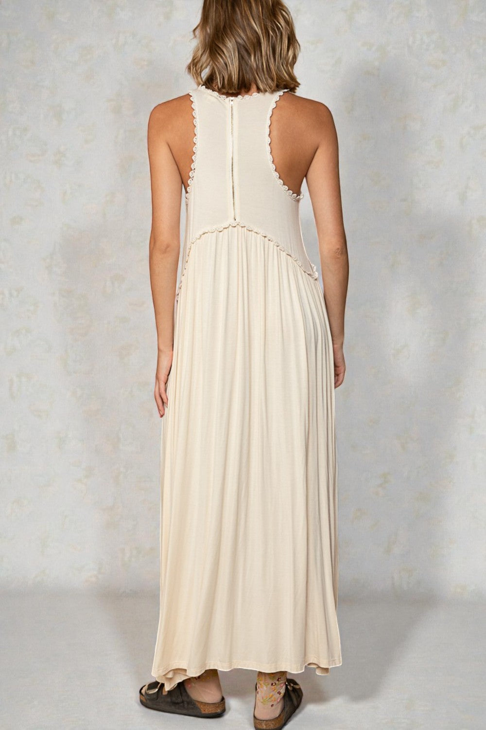 Woman wearing a beige sleeveless dress against a light background