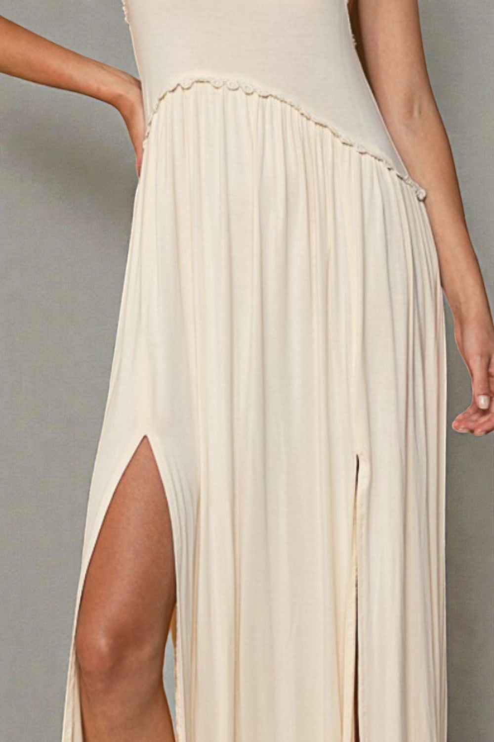 Beige pleated dress with a slit on a plain background