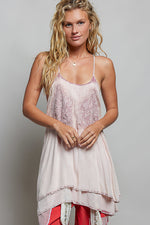 Woman wearing a light pink lace dress with red pants on a gray background