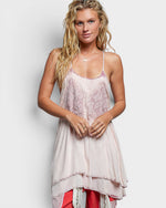 Woman wearing a light pink lace dress with a plain background
