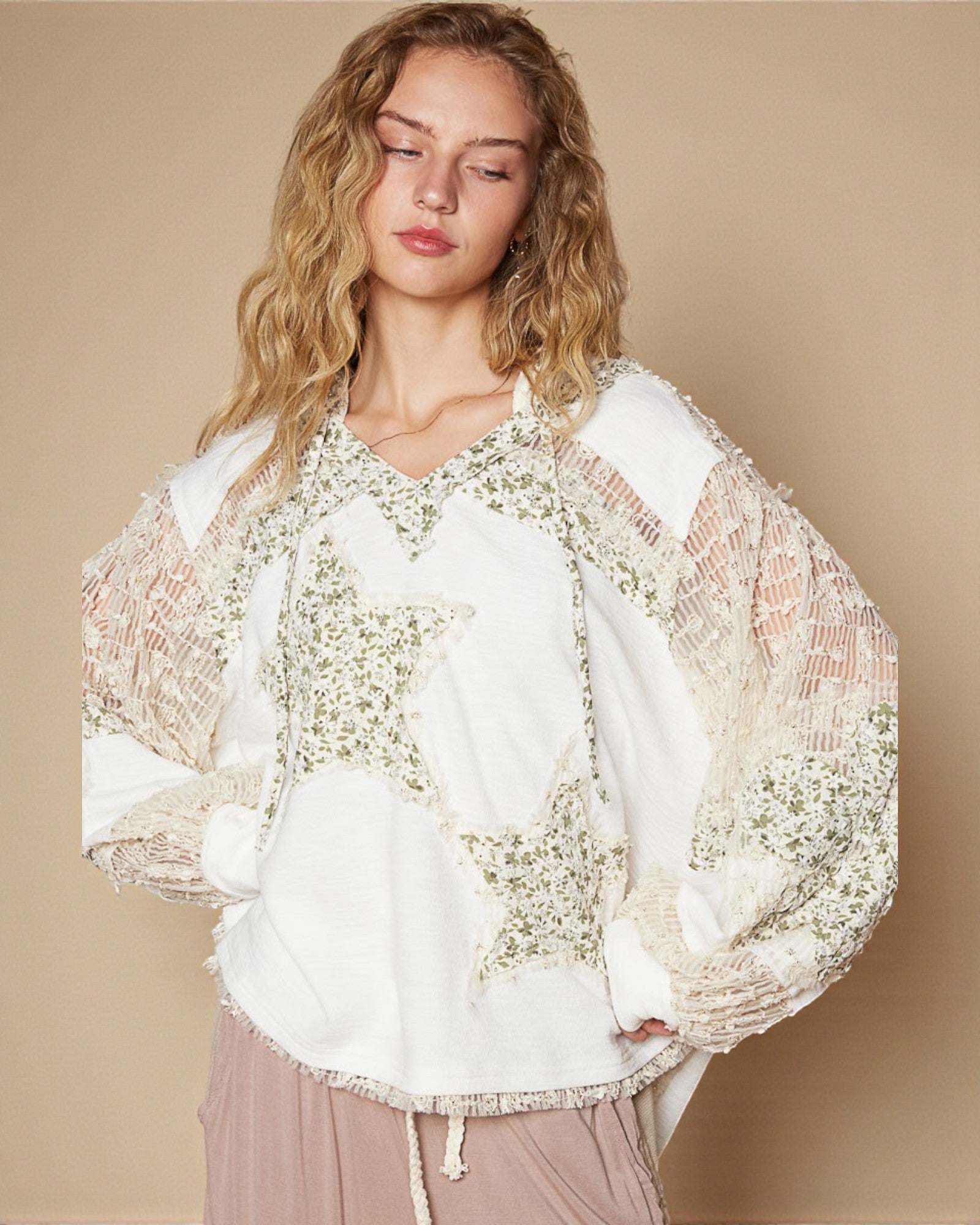 Woman wearing a white blouse with floral embroidery against a beige background