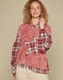 Woman wearing a red plaid shirt over a pink hoodie against a beige background