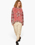 A model wearing a dusty pink and red plaid patchwork hoodie with a star patch, paired with beige distressed cargo pants and black shoes, against a plain white background.