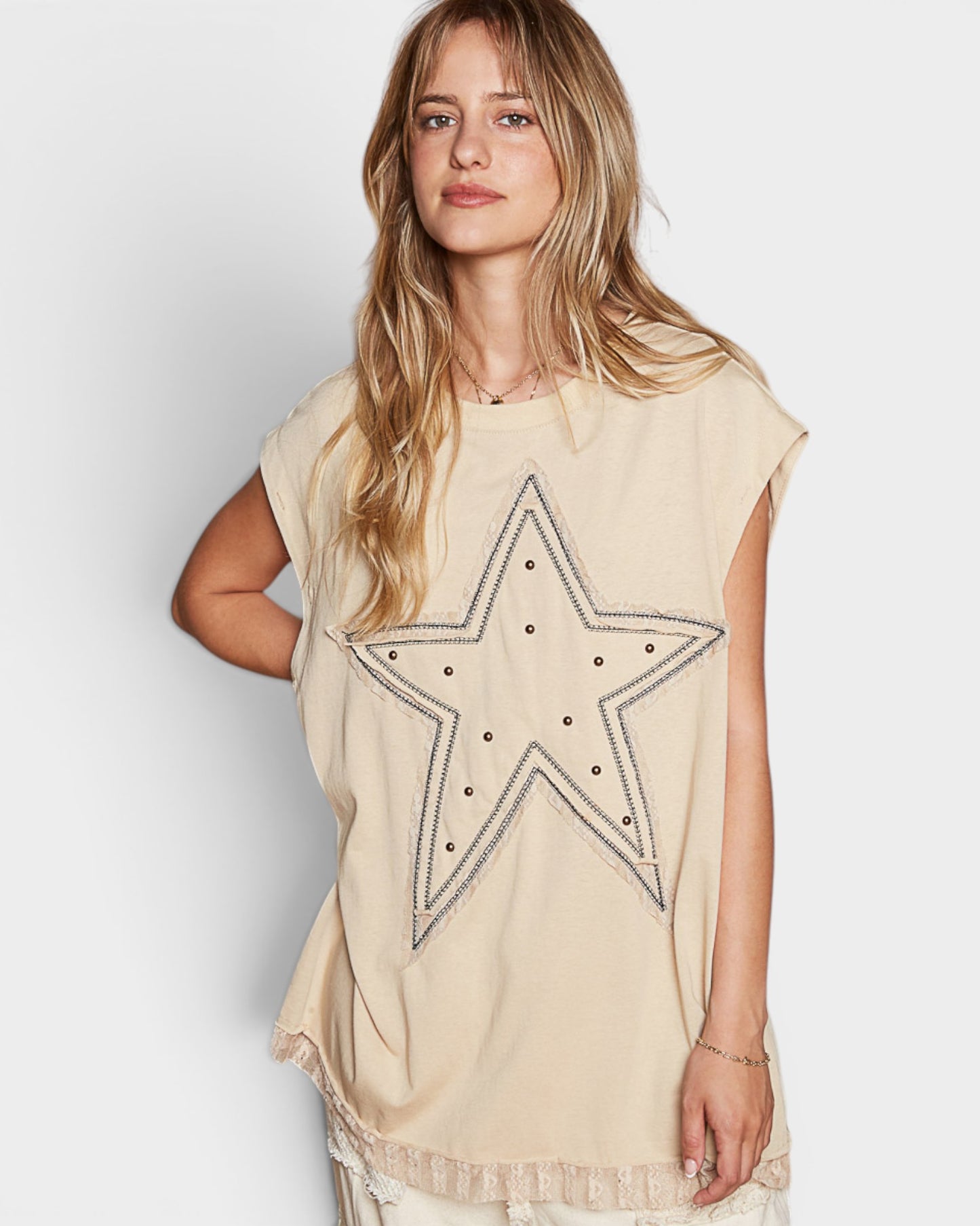 Woman wearing a beige tunic with a star design on a white background