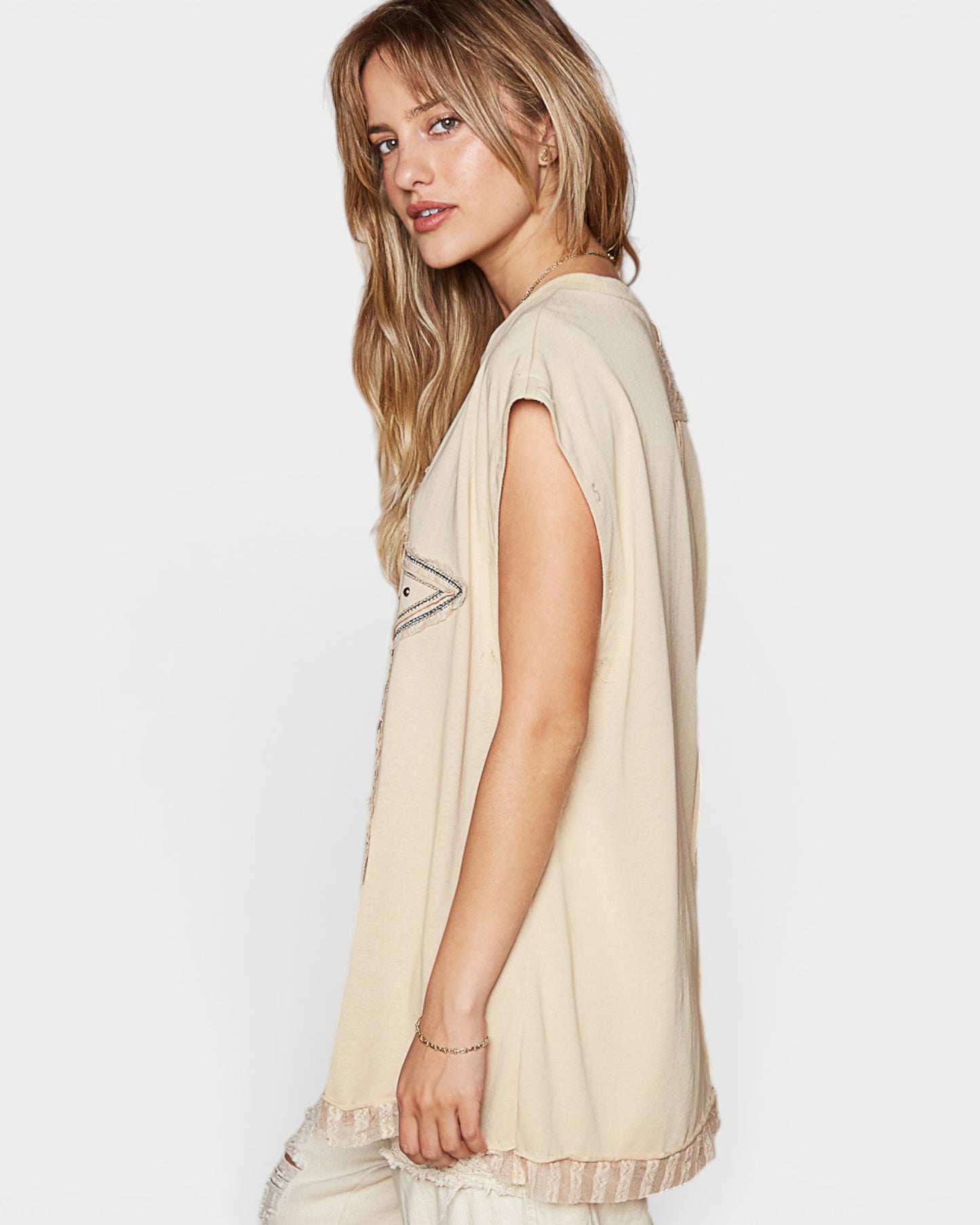 Woman wearing a beige sleeveless top with a subtle pattern on a white background