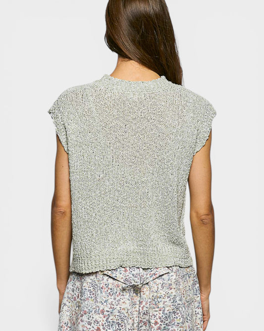 Woman wearing a light green knitted vest on a plain background