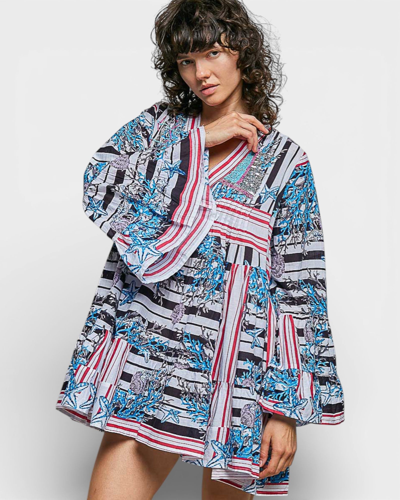 Woman wearing a patterned dress with a scarf on a white background