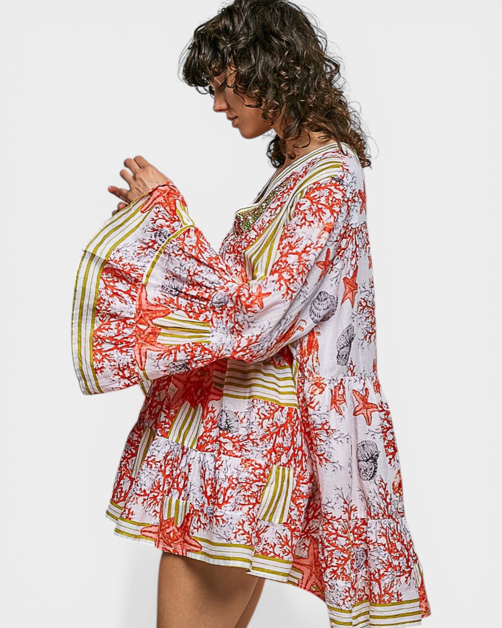 Woman wearing a colorful floral dress with bell sleeves on a white background
