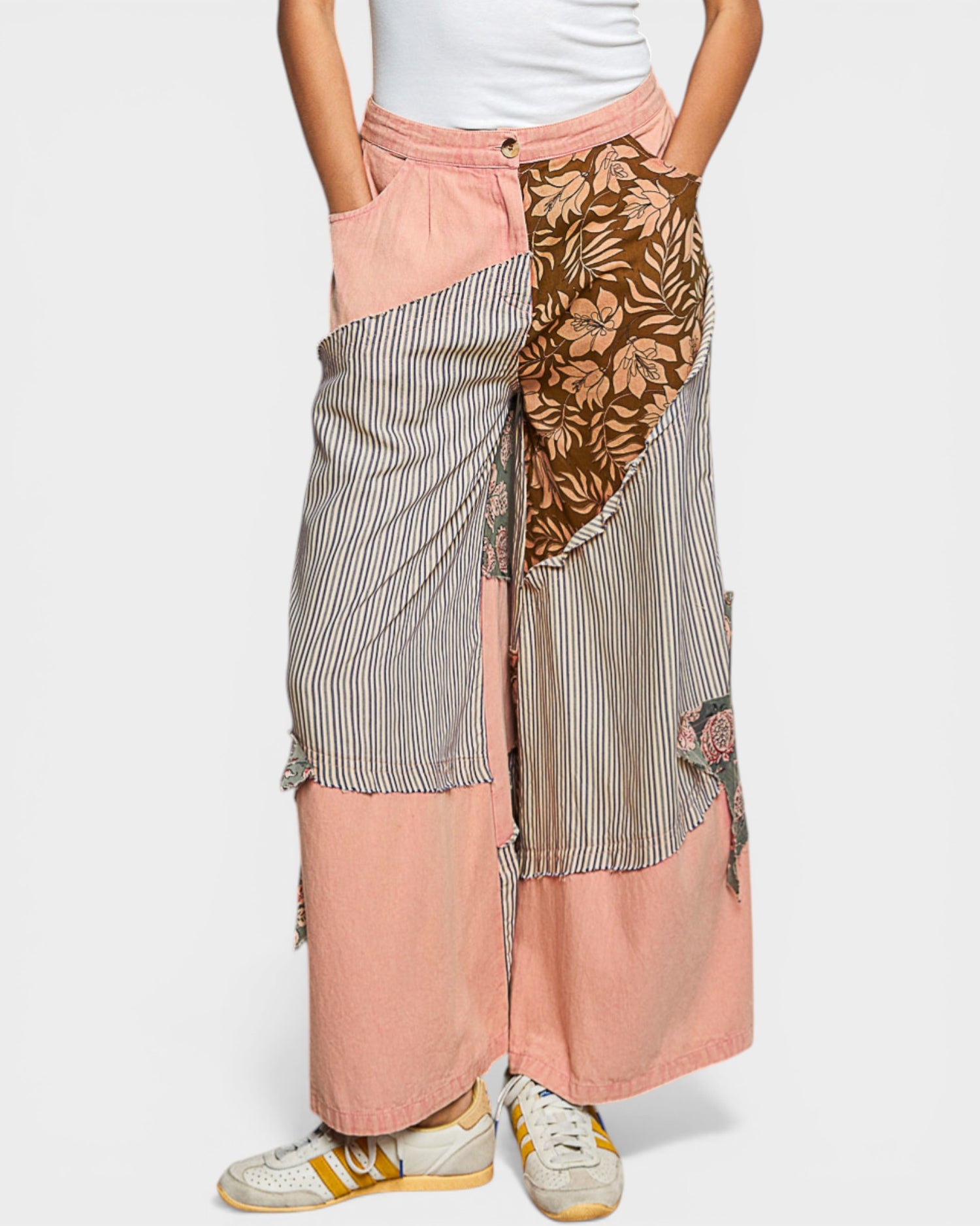 Person wearing a patchwork skirt with floral and striped patterns on a white background