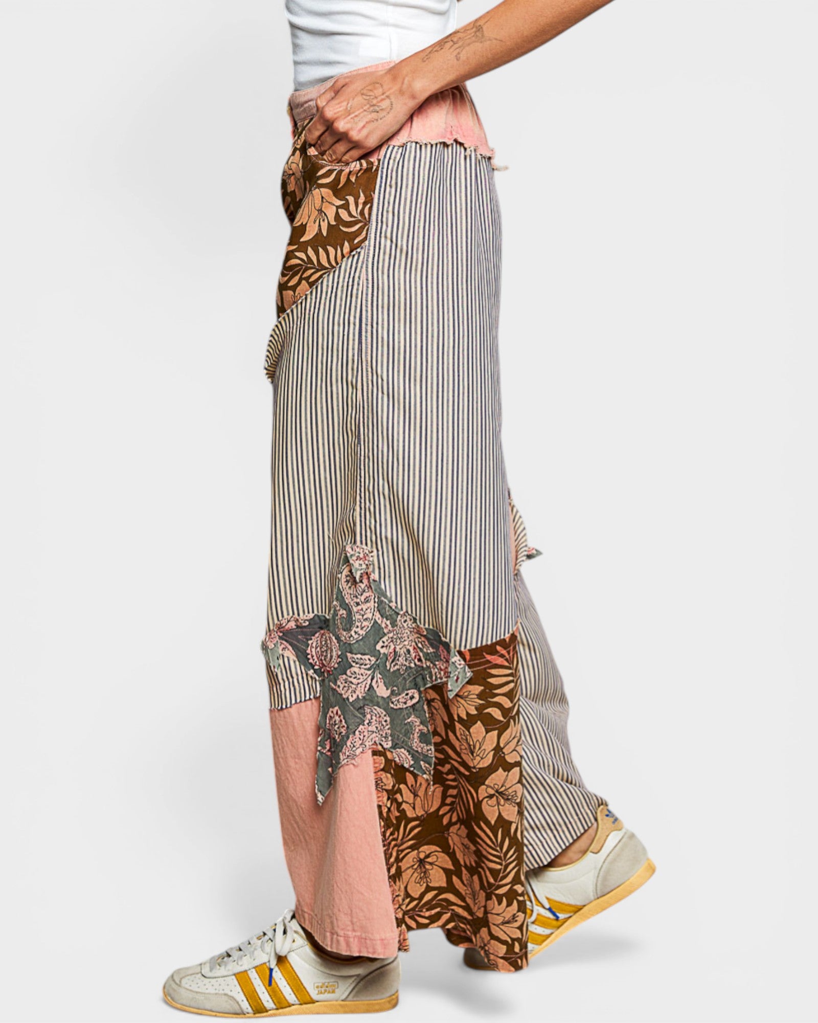 Person wearing a patchwork skirt with various patterns on a white background