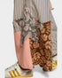 Person wearing a striped shirt with floral and animal print pants on a light gray background