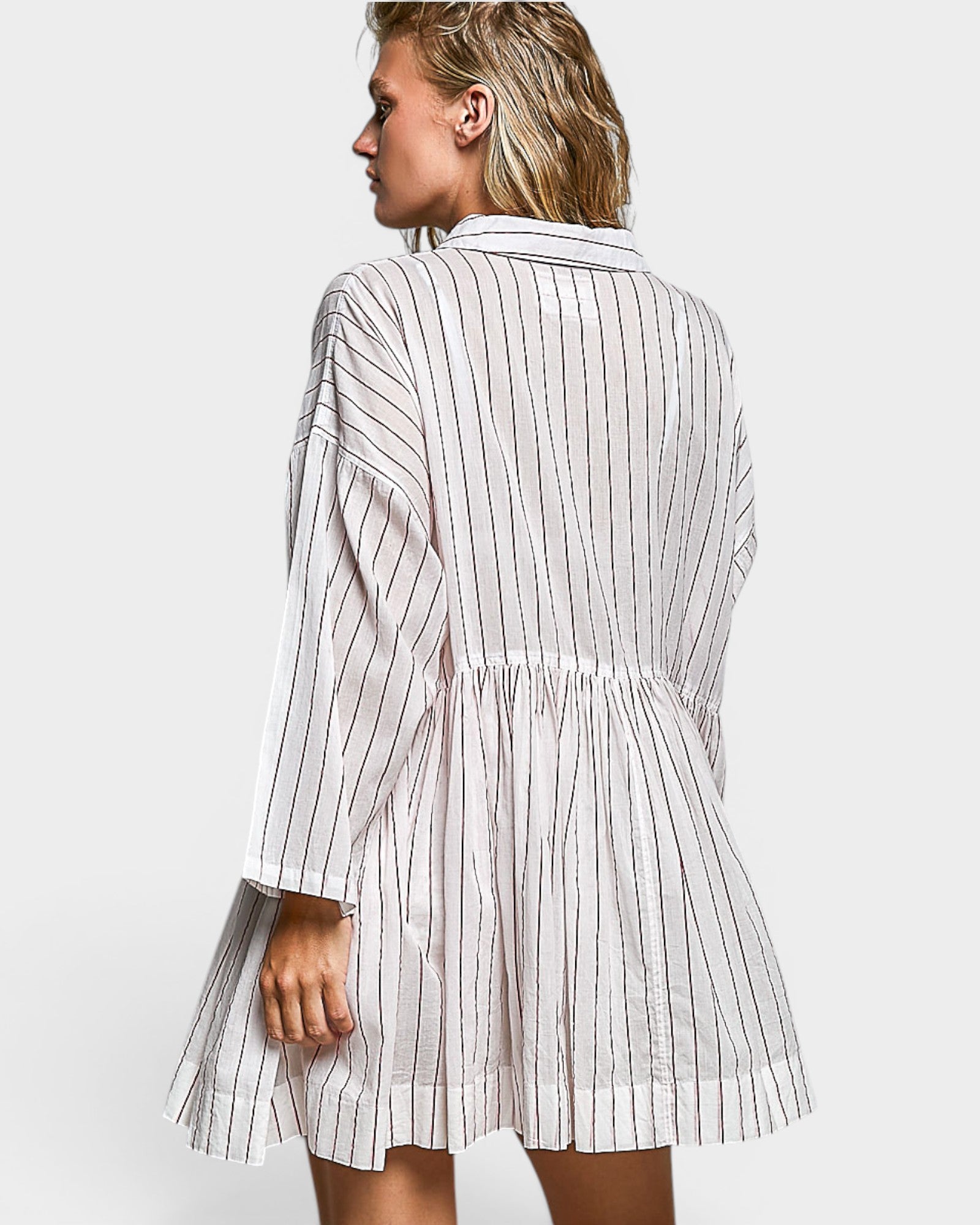 Woman wearing a white and black striped dress on a plain background