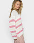 Woman wearing a white and pink striped sweater on a plain background
