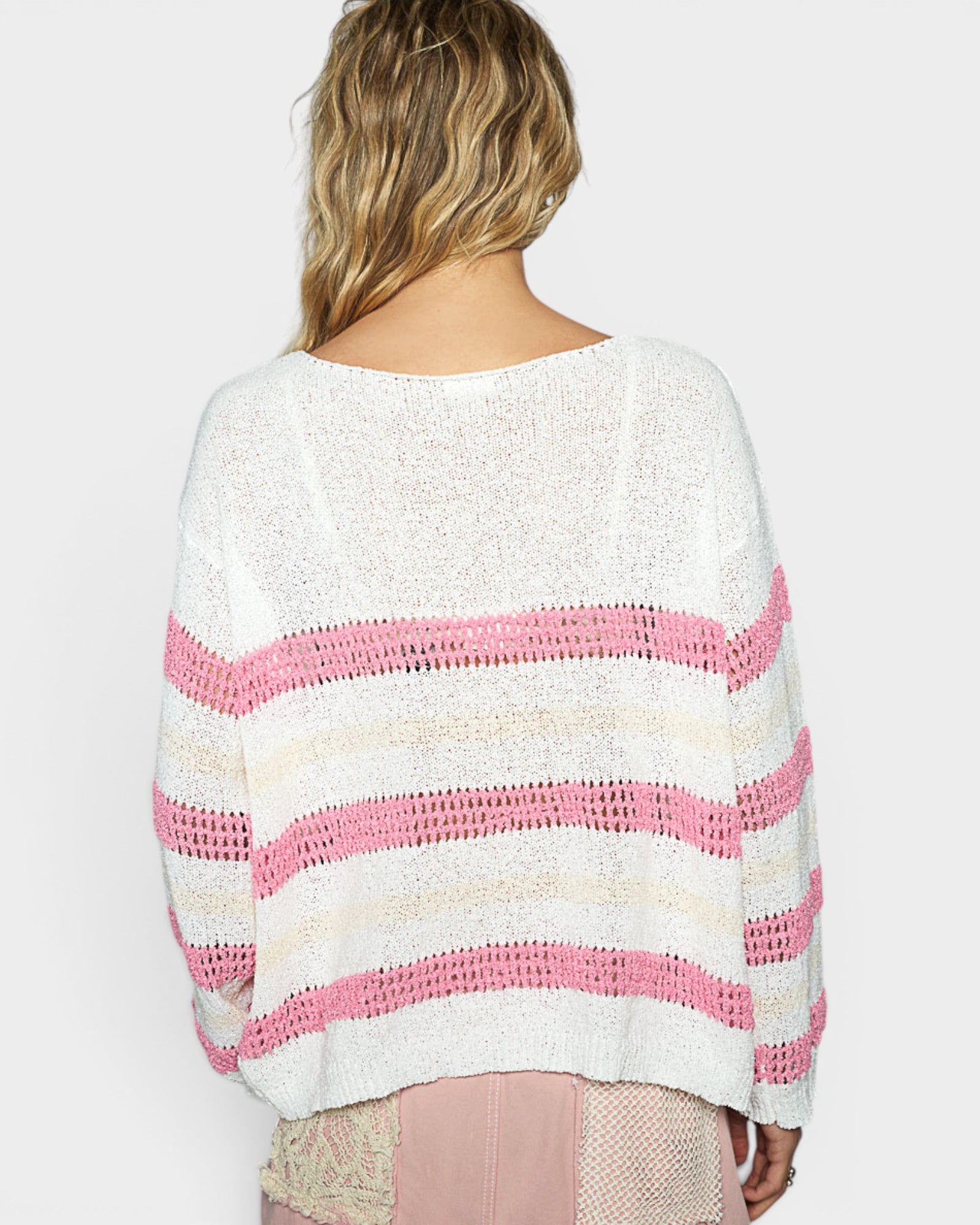 Woman wearing a white and pink striped sweater on a plain background